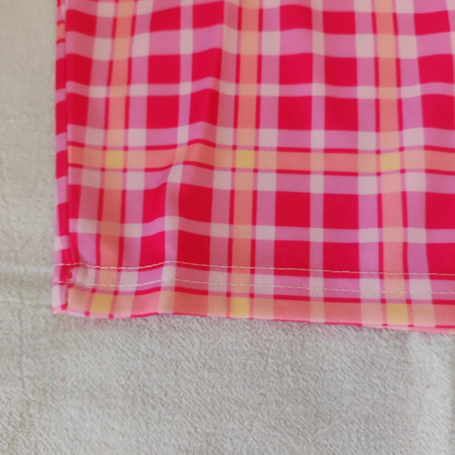 Close‑up bottom hem double line stitching and pink plaid fabric pattern