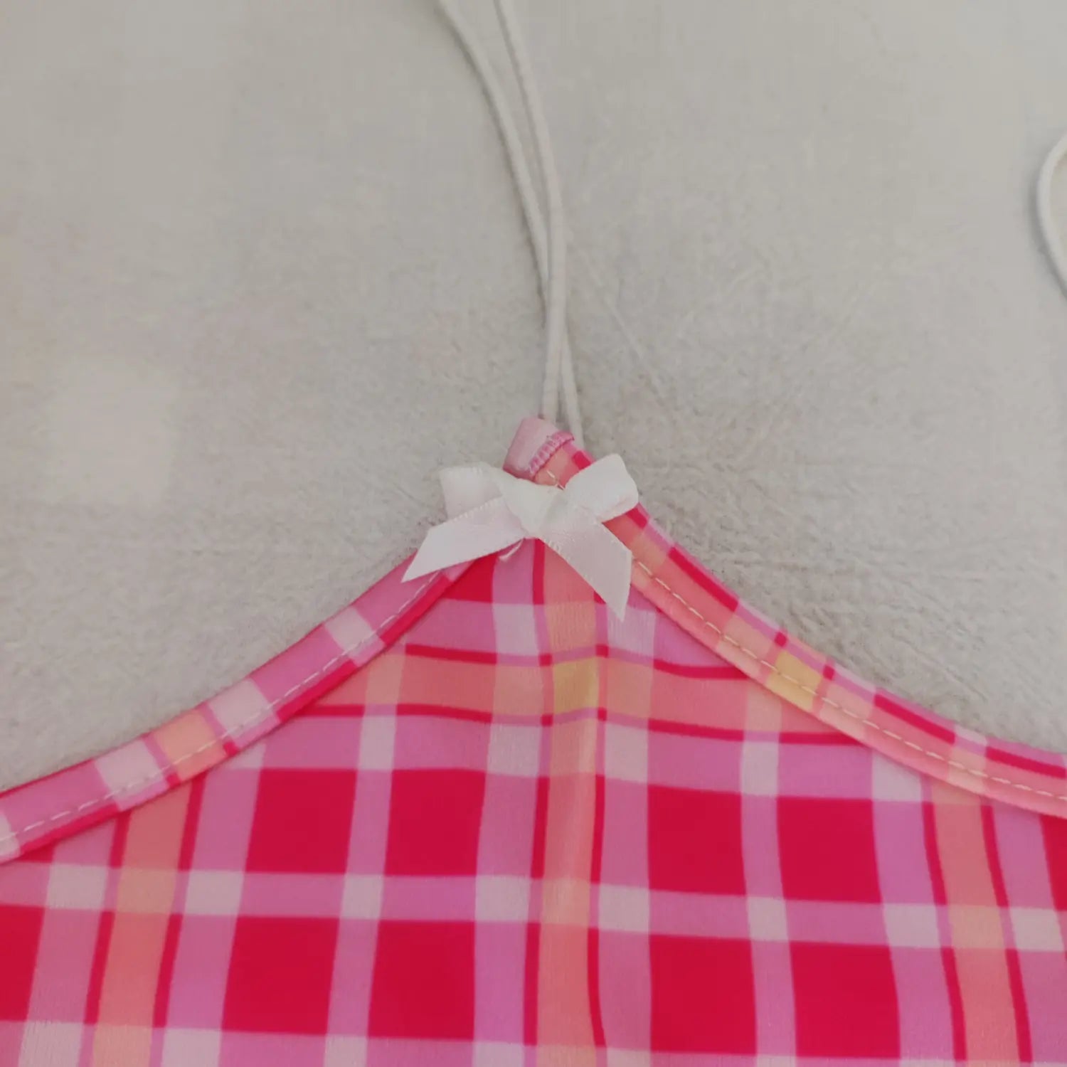 Close‑up shoulder white satin bow and seam stitching detail pink plaid crop cami