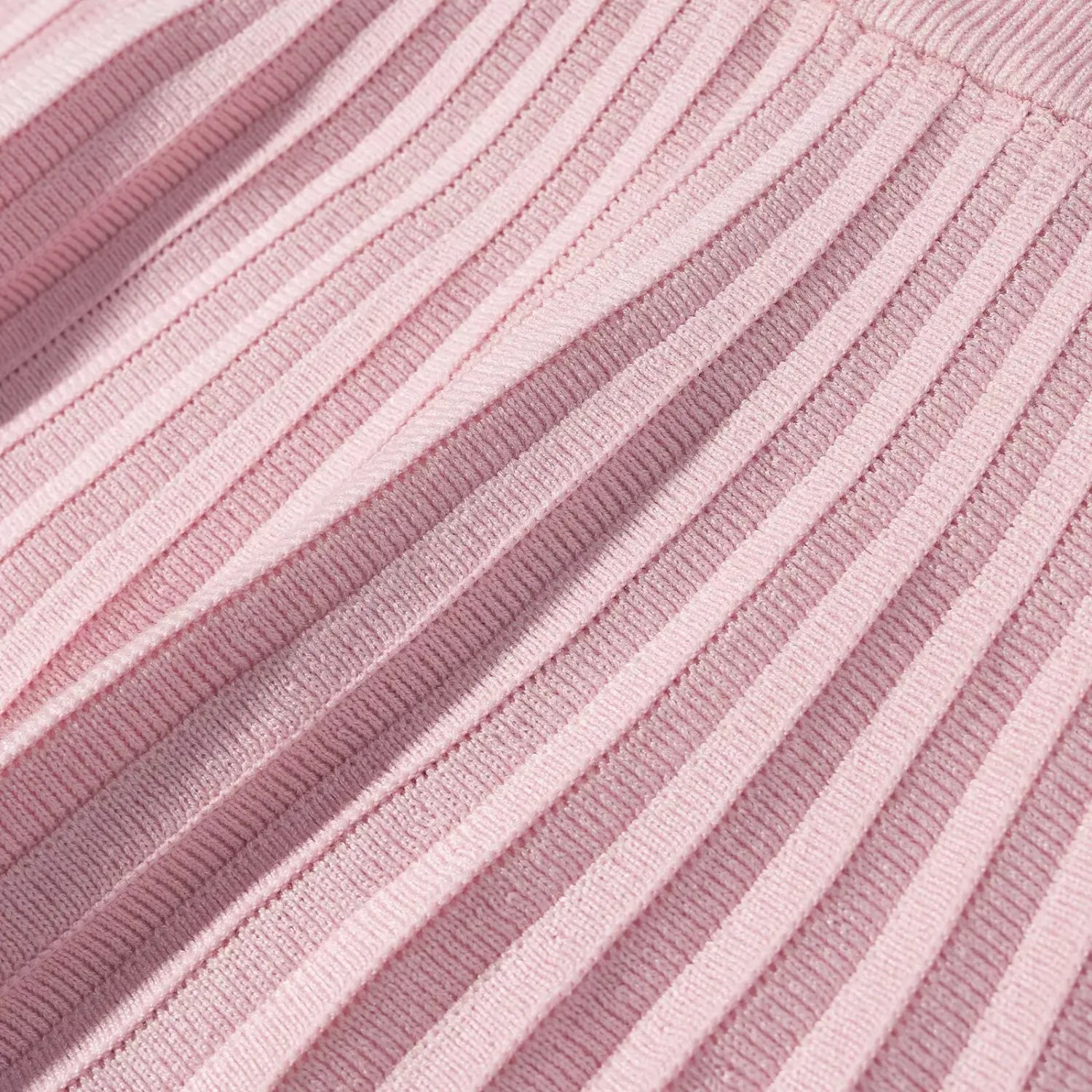 Macro shot of pink knit skirt vertical pleated ribbed fabric, light shadow showing pleat depth