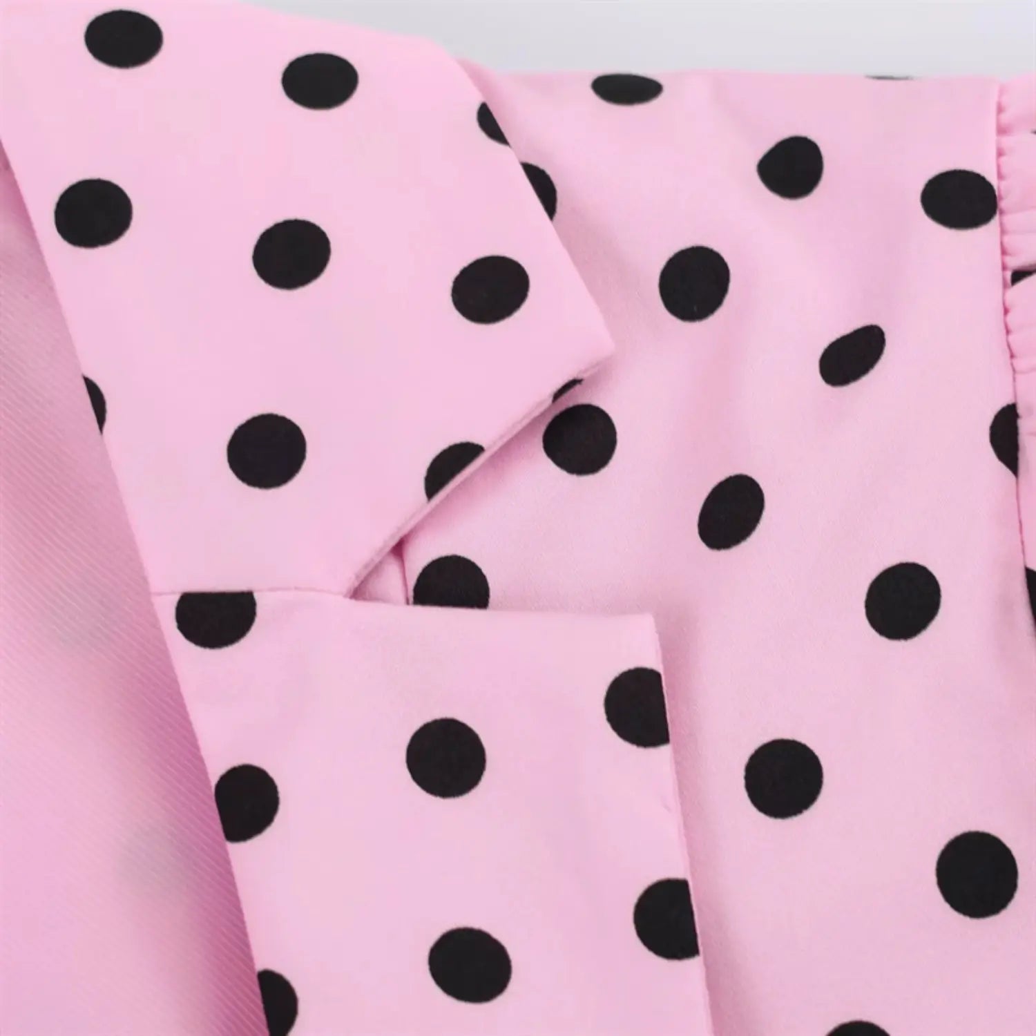 Notched lapel folded edge extreme close-up, neat folded seam workmanship, lightweight woven polka dot textile