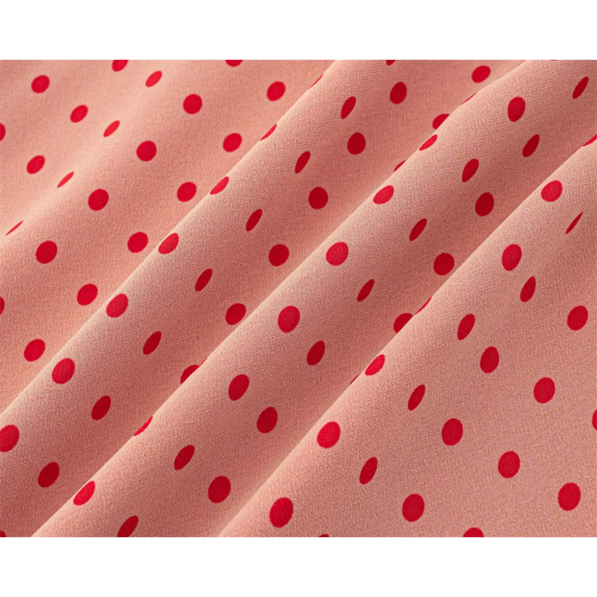 Close-up of the sheer fabric texture and red polka dot print on the pink dress.