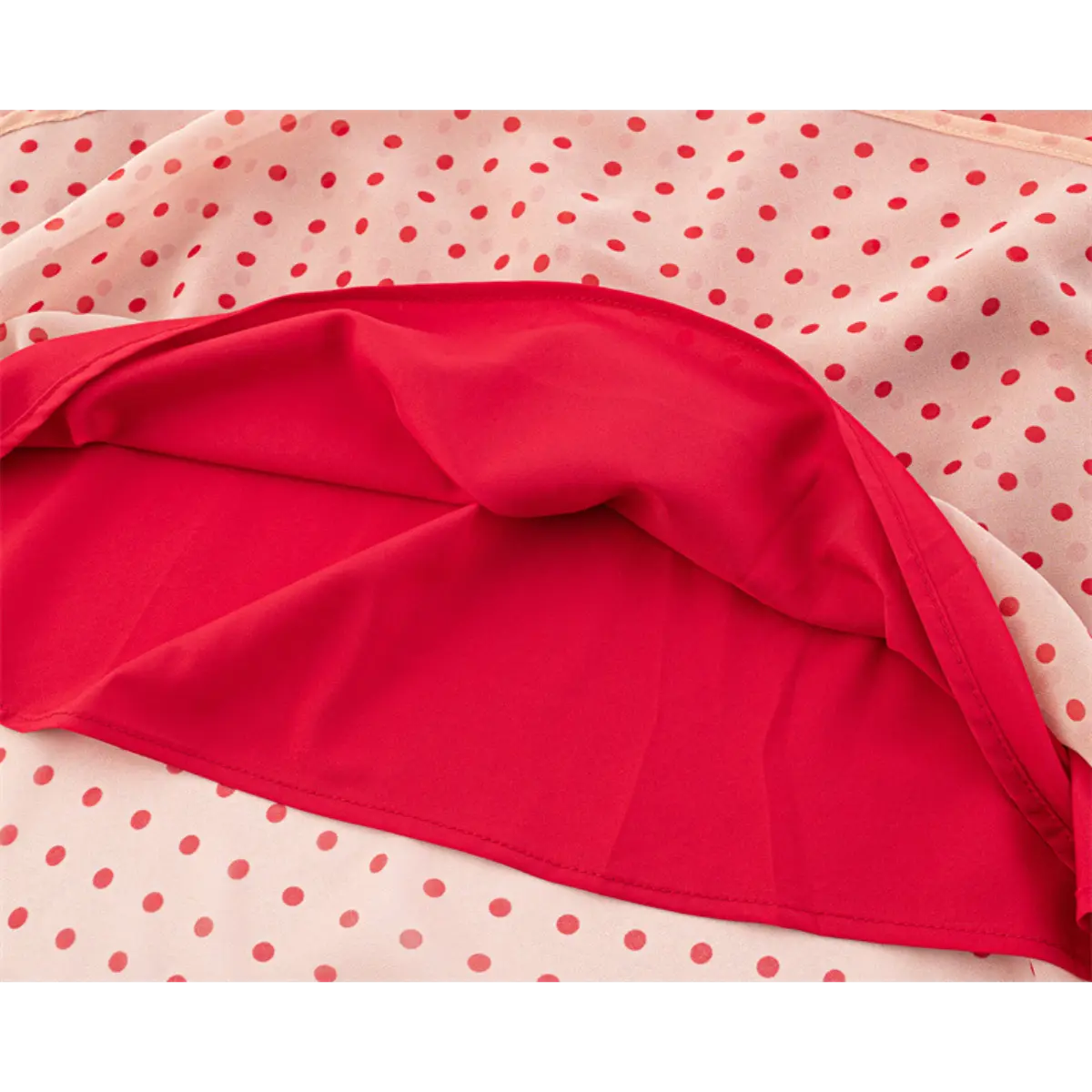 Close-up of the fabric texture and red inner lining on the pink polka dot dress.