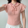 Model front view wearing pink polka dot chiffon blouse, ruffled collar tie and flutter sleeve styling