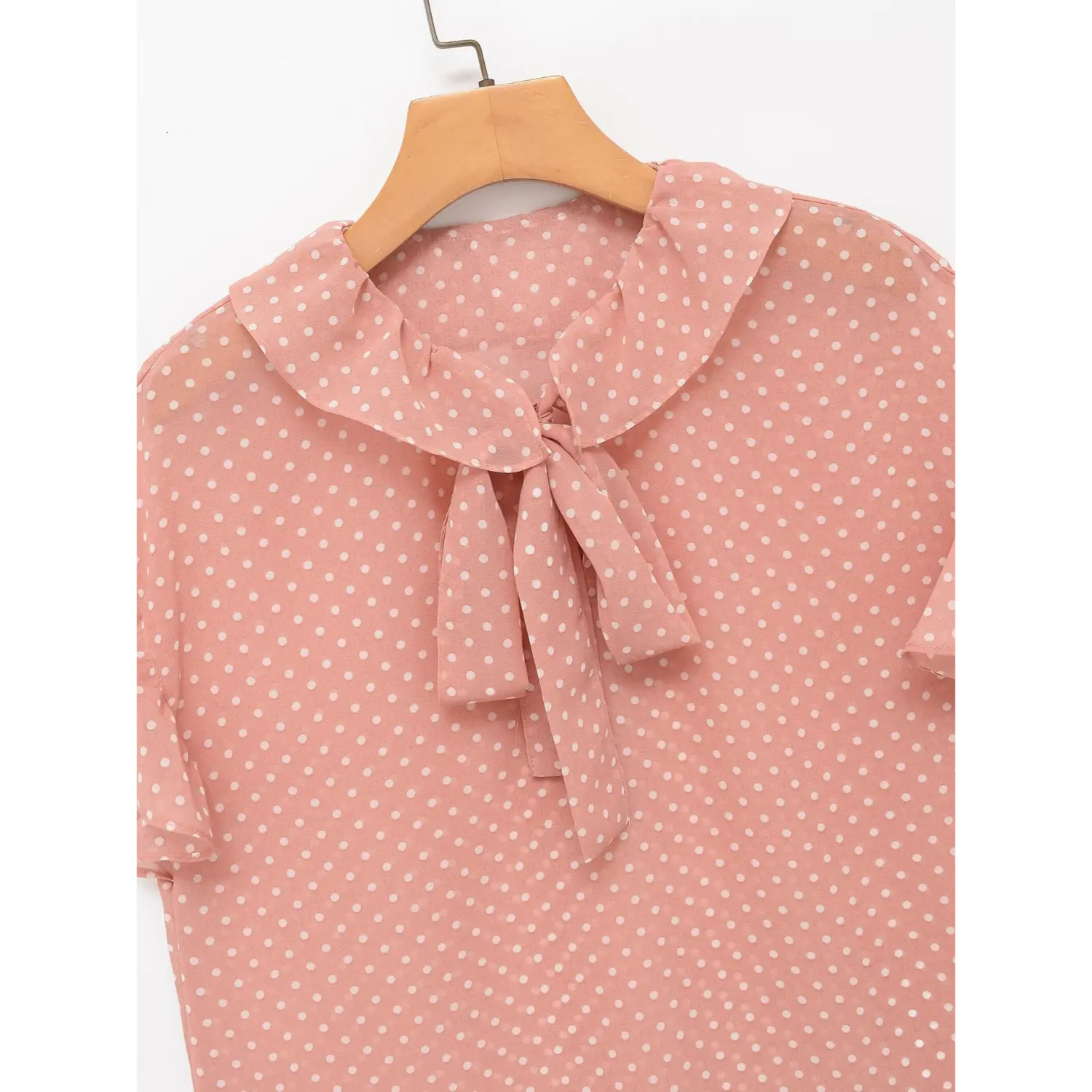 Close-up detail of blouse neckline, ruffled collar and front self-fabric tie bow, pink polka dot chiffon fabric