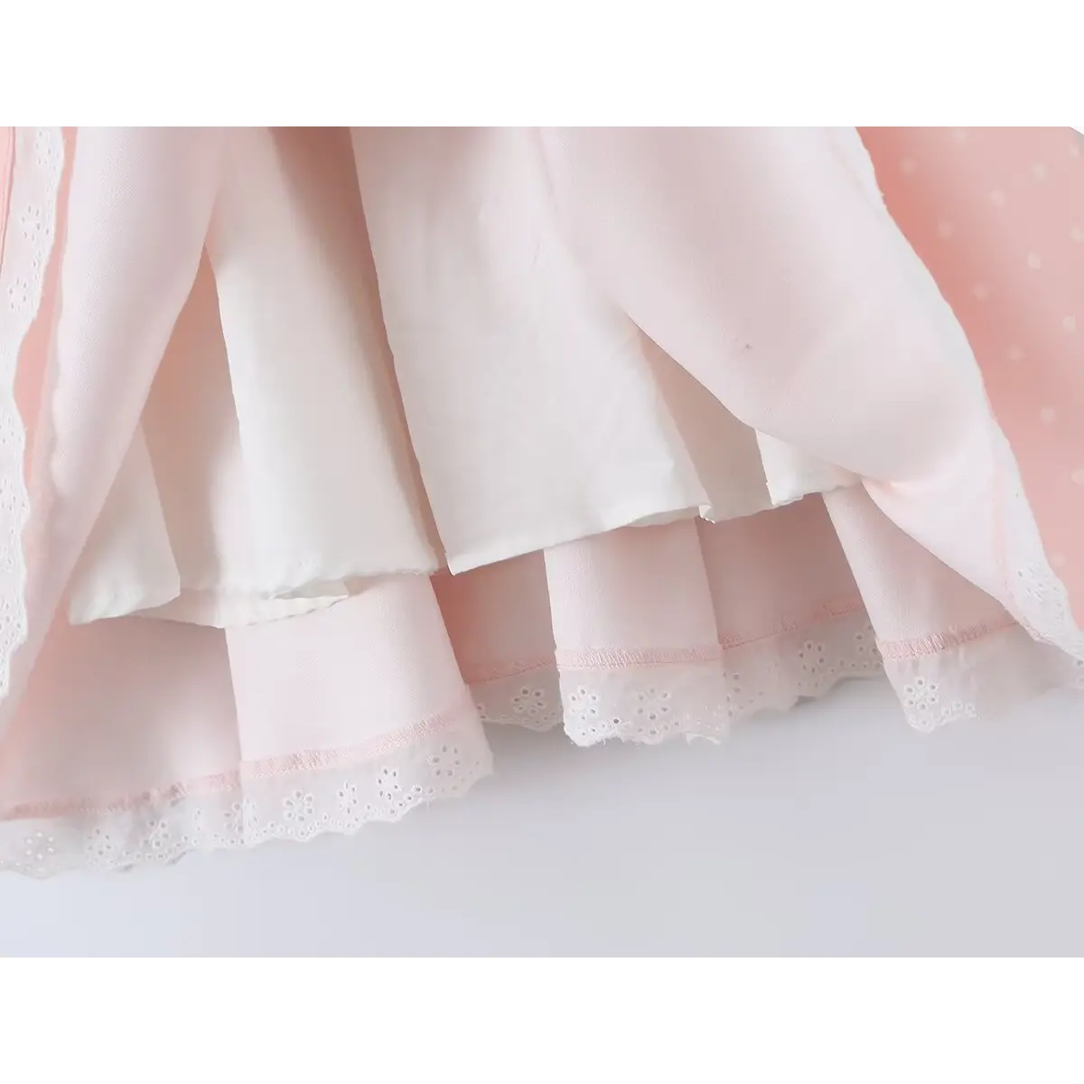 Close-up of the inner lining and lace-trimmed hem on a pink polka dot corset-style dress.