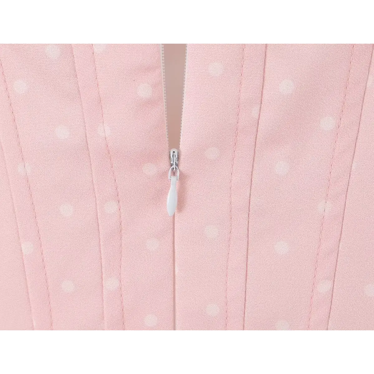 Close-up of the back zipper on a pink polka dot dress, showing the corset-style stitching.