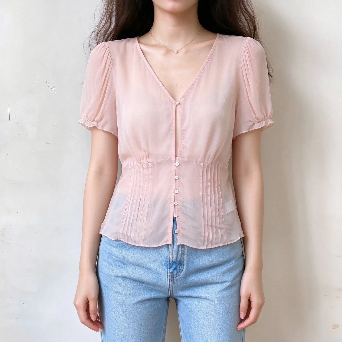 Model wearing pink sheer blouse, v-neck, short puff sleeves with ruffle cuffs, front button placket, waist pleated detail, lightweight semi-sheer fabric