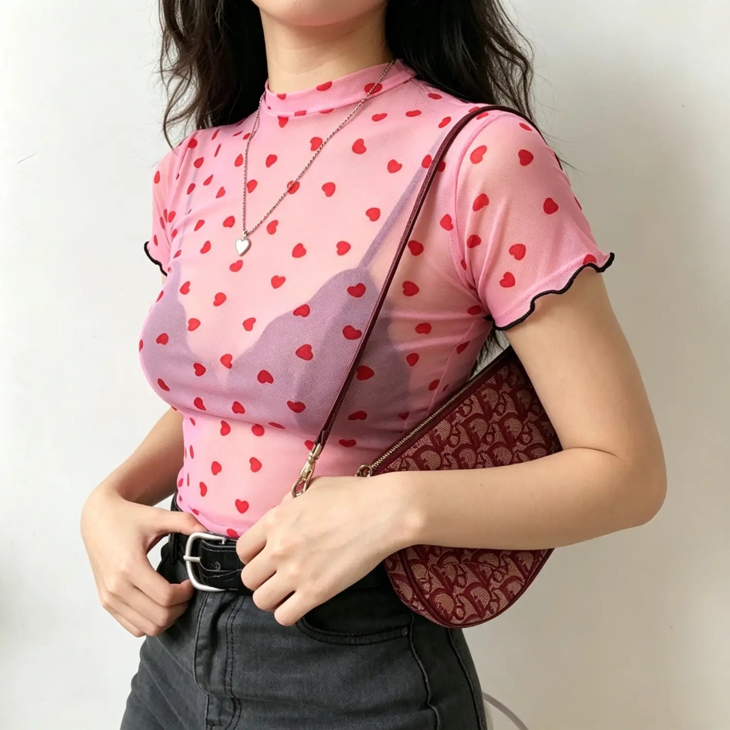 Model front view pink sheer mesh short sleeve top with all over red heart print and black ruffle trim