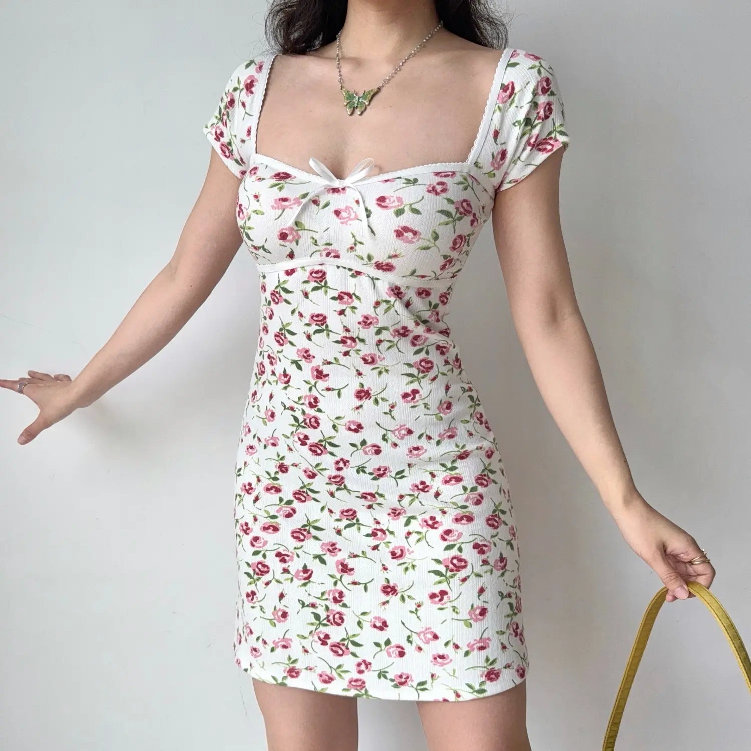 Front lifestyle shot on model of white floral ribbed dress, cap short sleeves, sweetheart neck with mini bow, casual summer mini dress