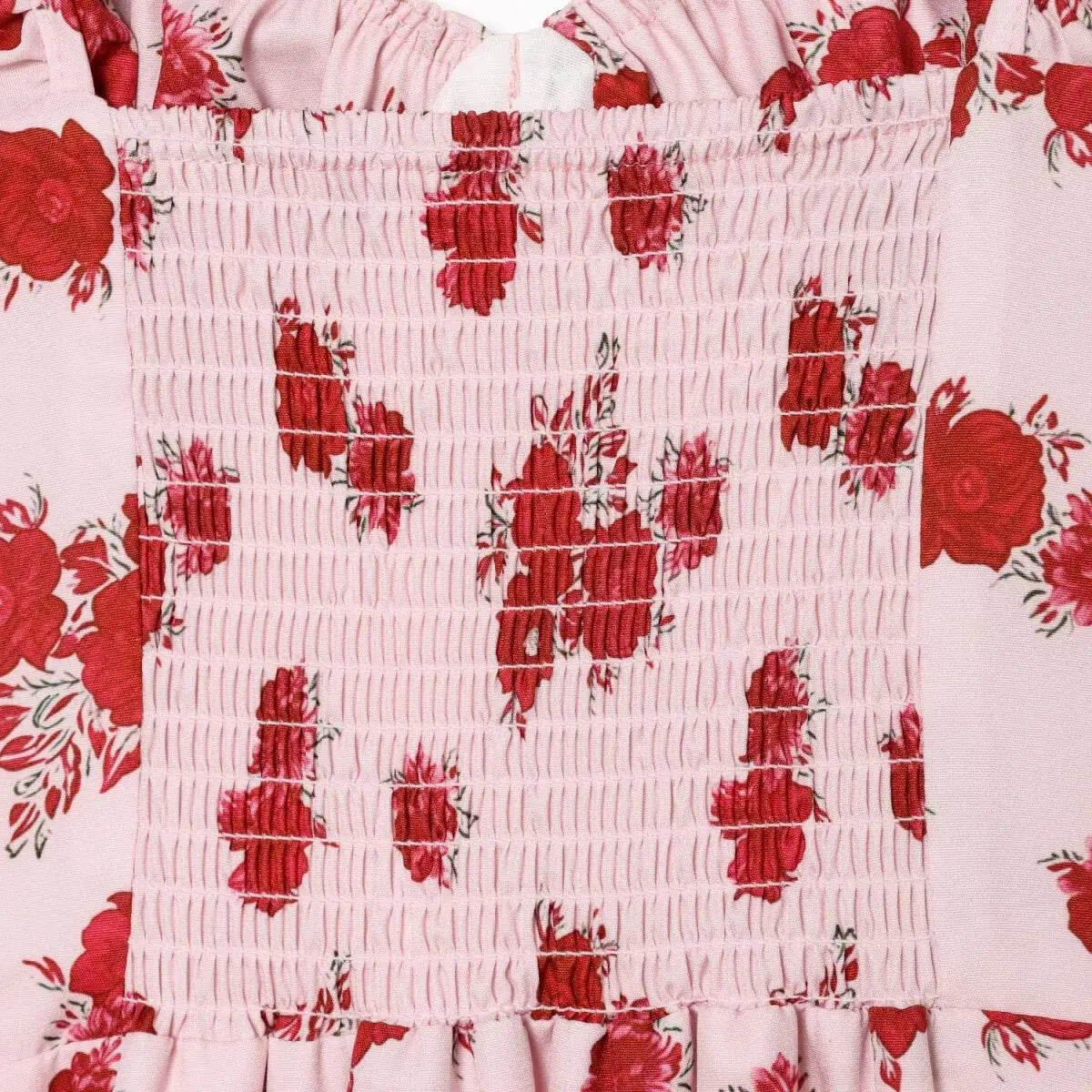 Close-up of the smocked back panel and rose print pattern on the pink cami dress