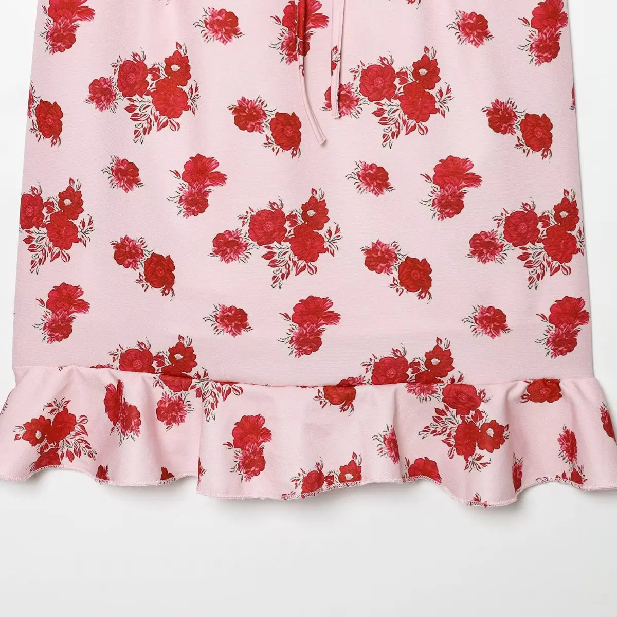 Close-up of the ruffled hem and floral print on the pink rose cami dress