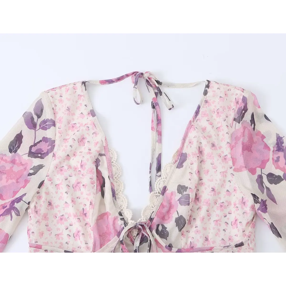 Close-up of the dress's front neckline, featuring the deep V-neck, lace trim, front tie, and open-back halter strap.