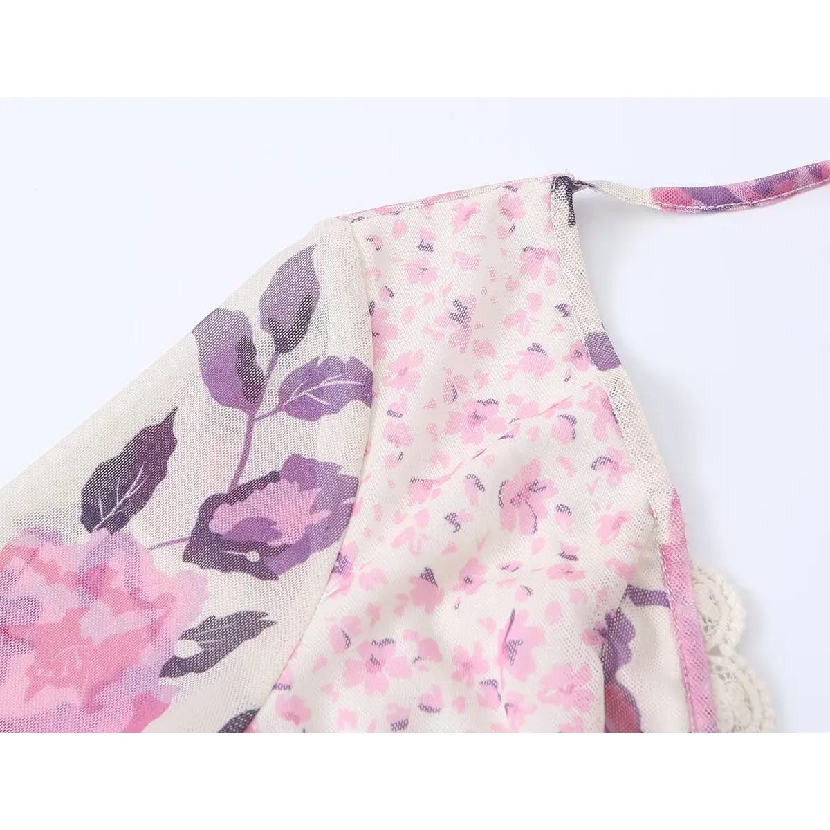 Close-up of the dress's shoulder and neckline, showing the lace trim, the halter strap, and the floral print.