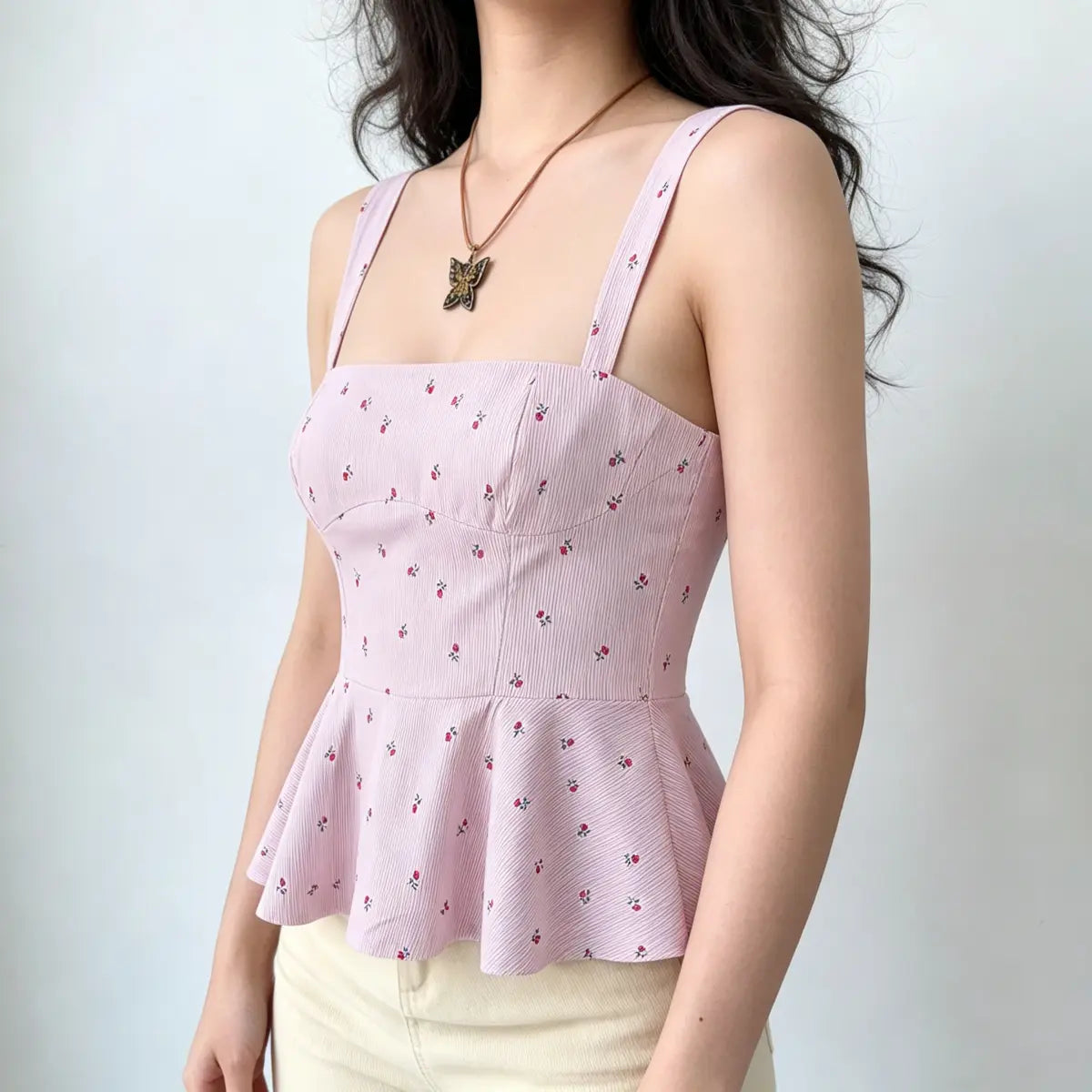 Front view of a light pink rose-print peplum cami top, highlighting the wide straps, square neckline, and subtle ribbed texture.