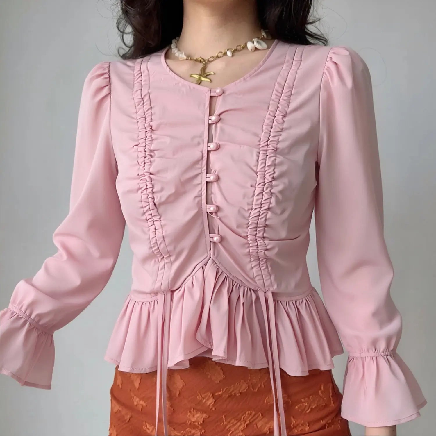 Model front view wearing pink ruched bell sleeve cropped blouse