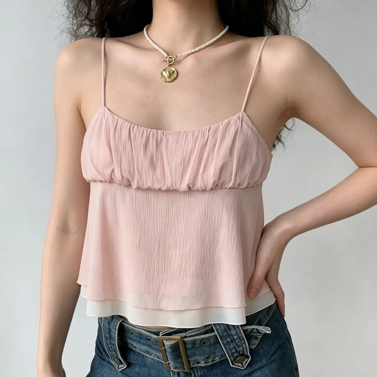 Side view of a light pink ruffled cami top, showcasing the double-layer design, gathered bust, and soft crinkled fabric texture.
