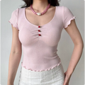 Close-up of the pink knit top showing the rose bud buttons, scoop neckline, and textured ribbed pattern