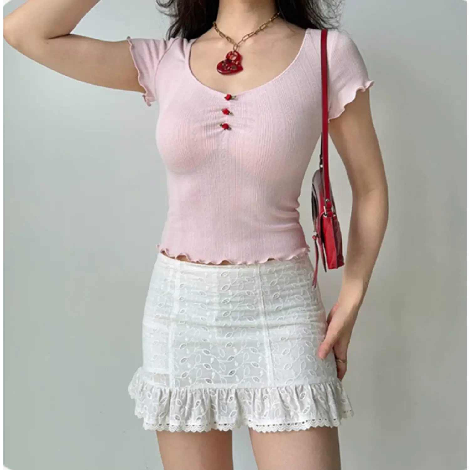 Model in profile wearing the pink ribbed knit top with scalloped edges, paired with a white lace ruffle skirt
