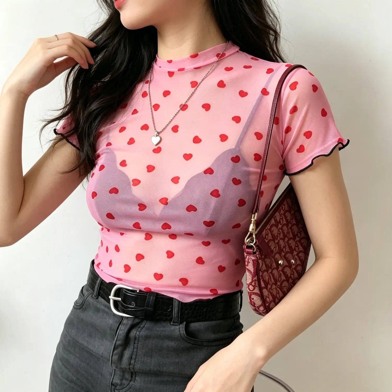 Model casual pose pink high neck sheer mesh top covered with red heart pattern
