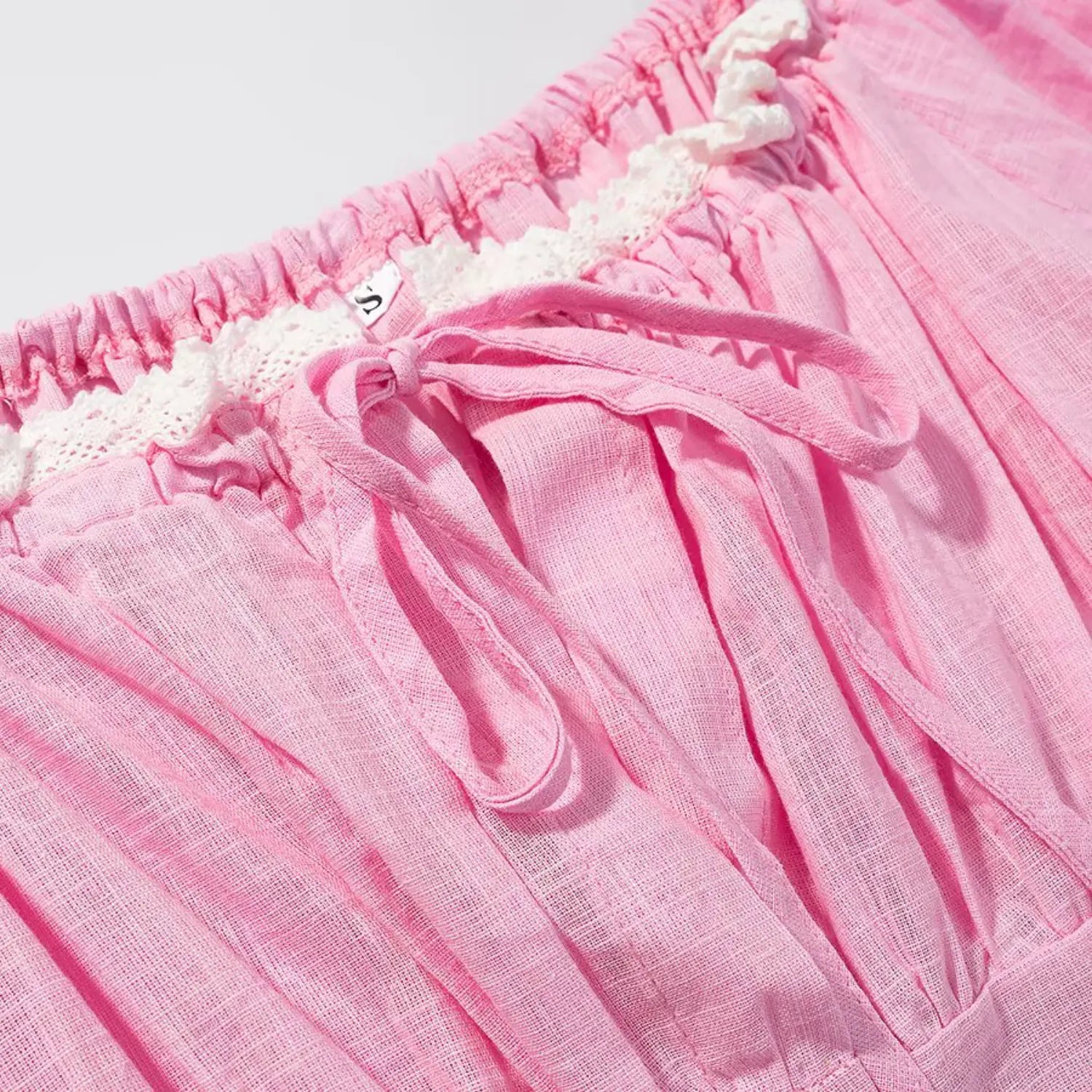 Waistband close-up, elastic gathered waist, hollow white lace edging, matching fabric drawstring tie, inner size label
