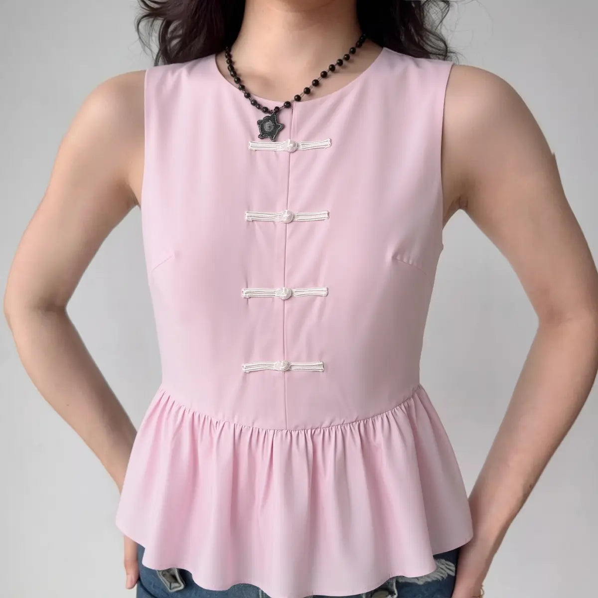 The top styled on a model, highlighting its fit, frog closure details, and peplum silhouette.