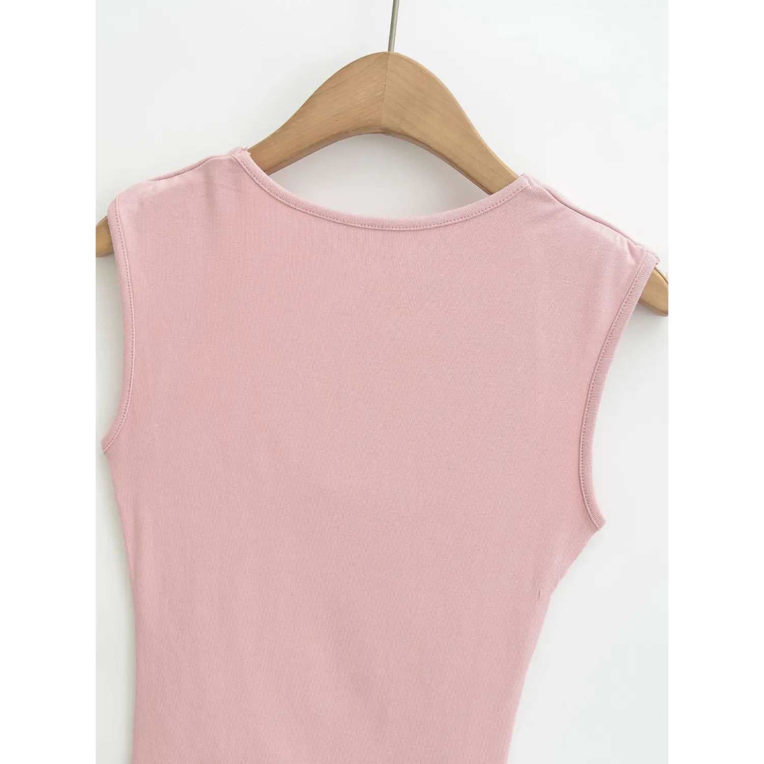 Full hanging back shot of dusty pink ribbed sleeveless tank top on wooden hanger, smooth plain rear panel