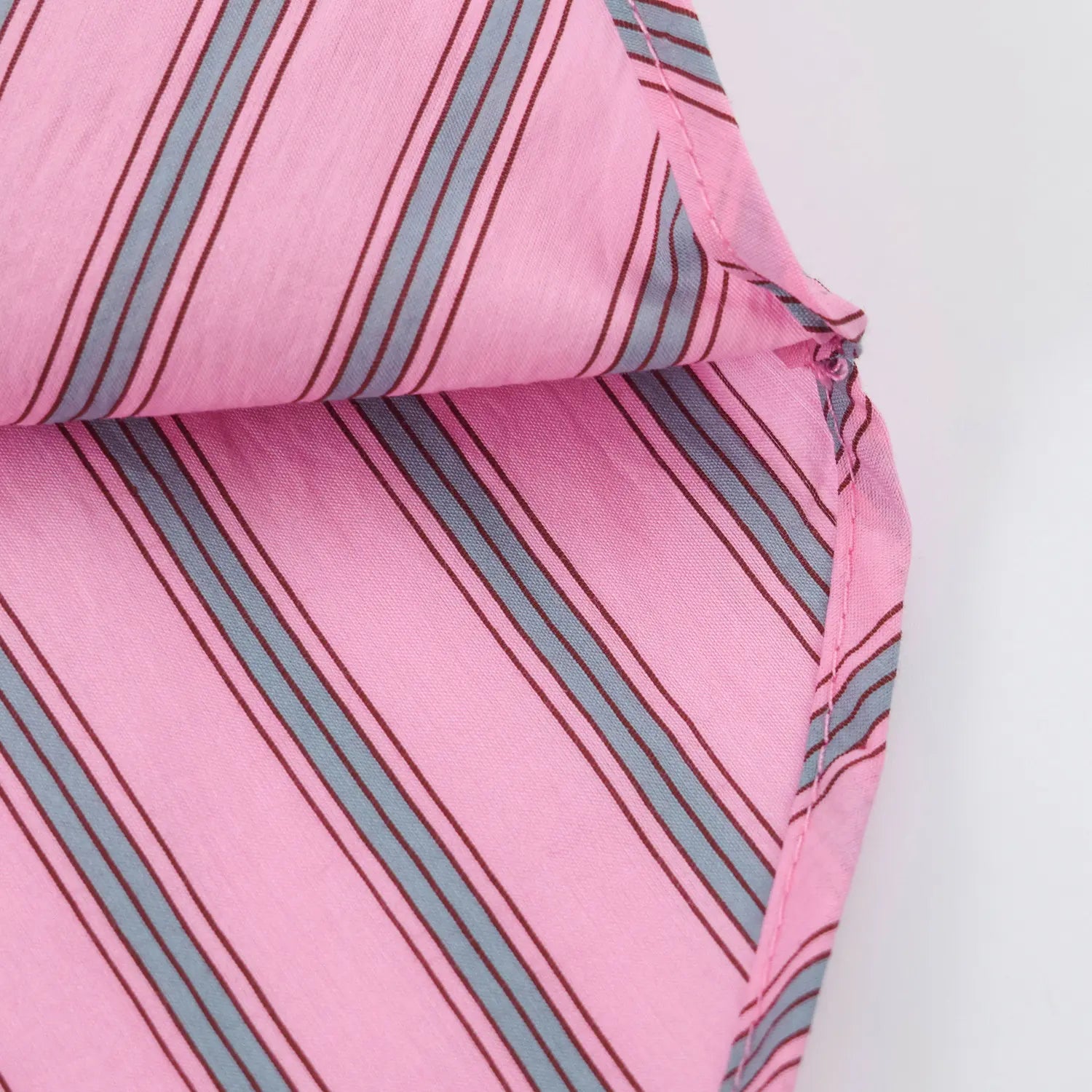 Closeup side hem finished seam, neat overlock stitching, vertical stripe lightweight woven fabric