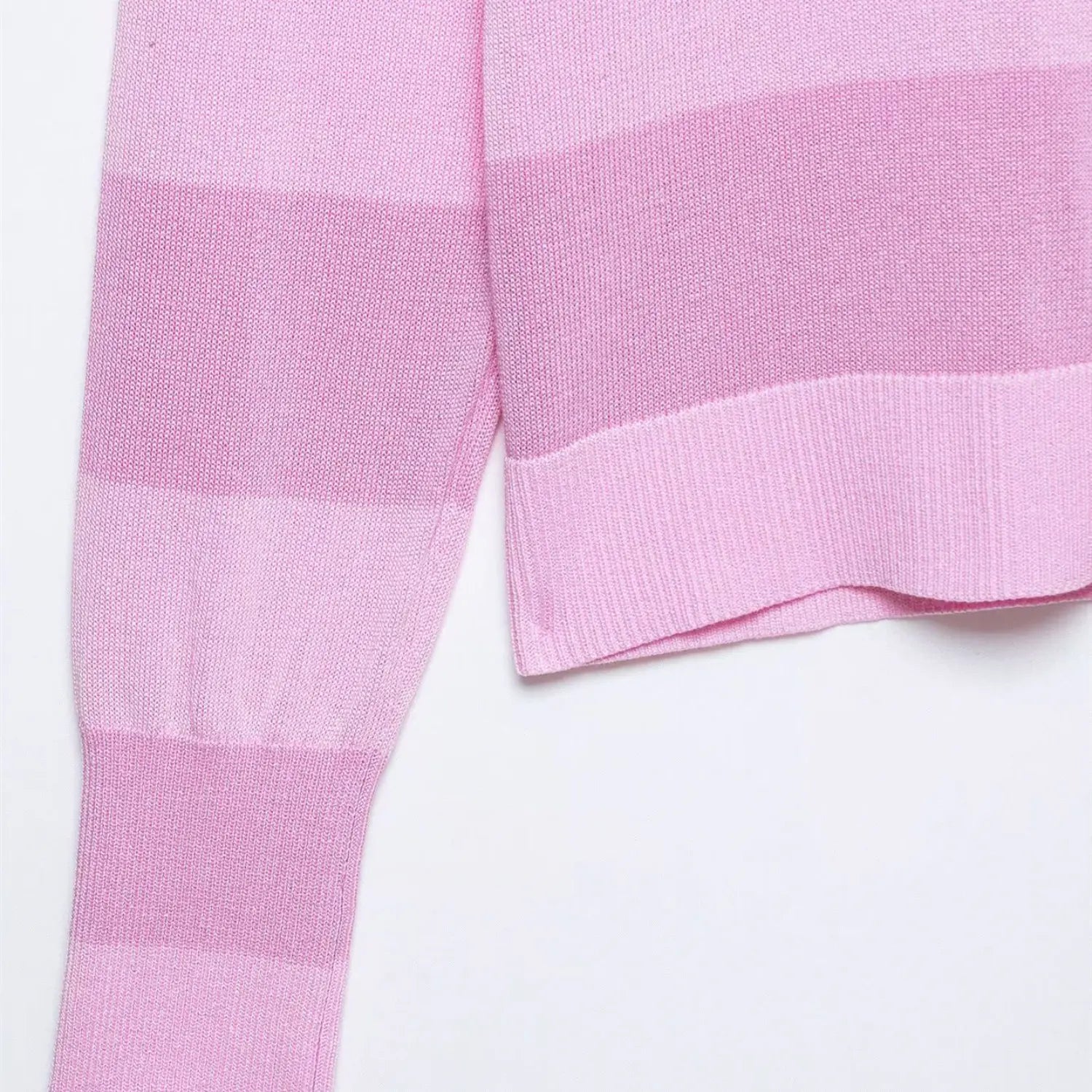 Close-up of the side seam, hem, and stripe pattern on the pink knit cardigan