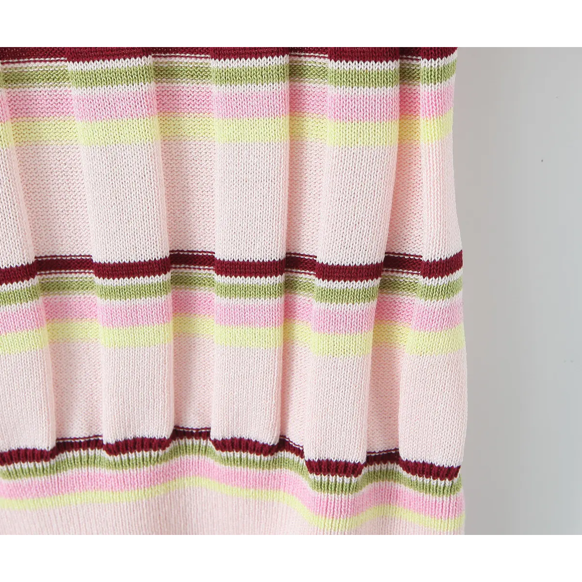 Close-up of the fabric texture on the pink knit polo, showing the vertical ribbing and multicolor stripe pattern