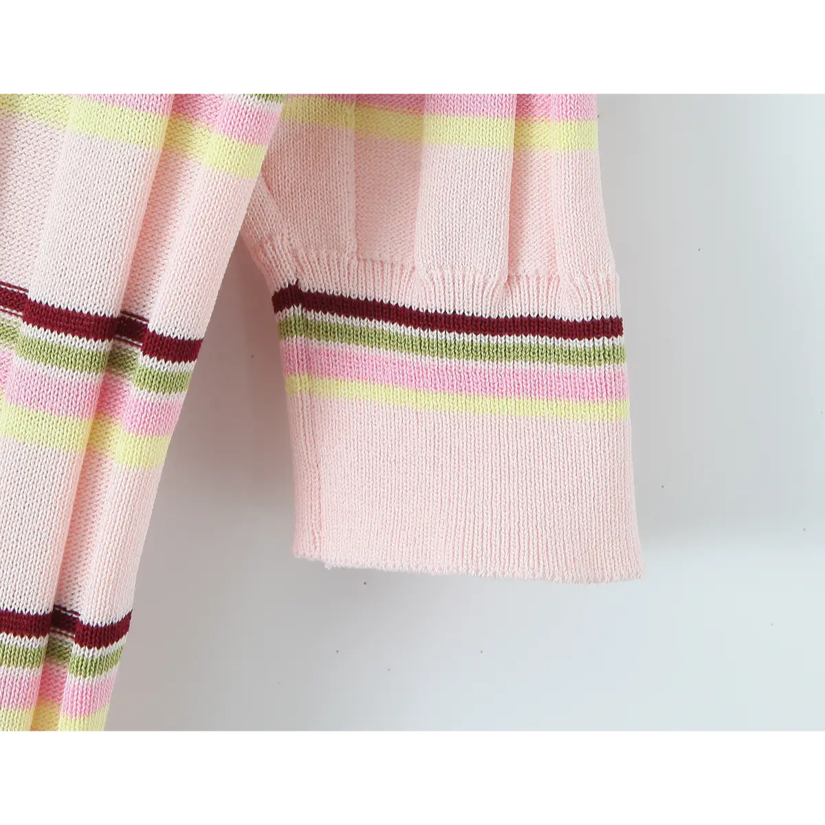 Close-up of the short sleeve on the pink striped knit polo top, showing the multicolor stripe pattern and ribbed cuff