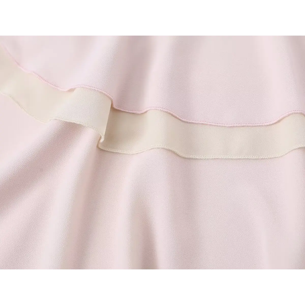 Close-up detail of a pink tiered chiffon skirt, showing the contrast between the pink outer layer and beige inner lining.