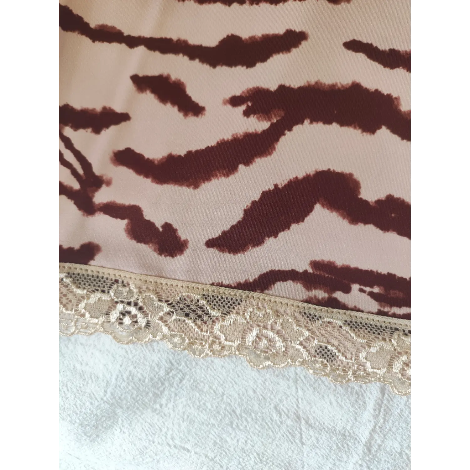 Close-up of beige floral lace hem and pink zebra stripe fabric texture