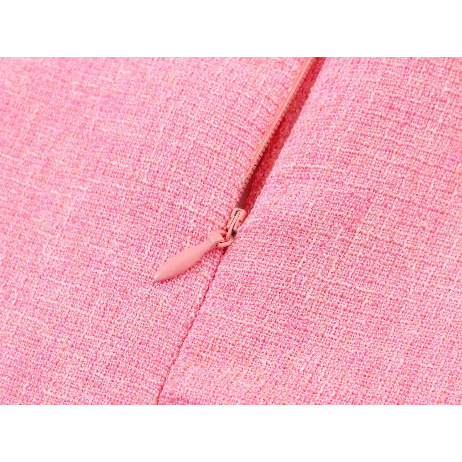 Close-up of pink matching invisible back zipper with elongated fabric pull tab embedded in tweed seam