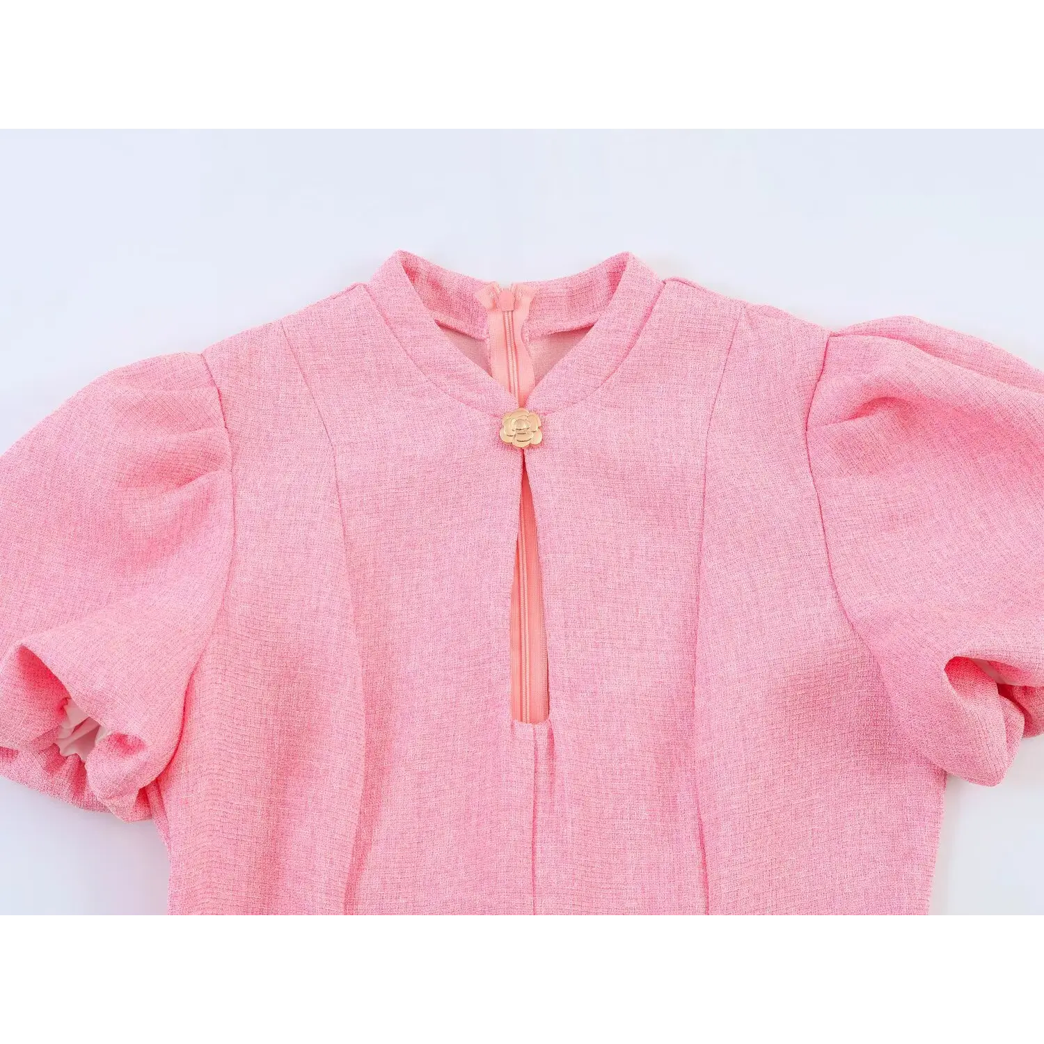  Close-up of front stand collar keyhole cutout, fixed with gold camellia decorative clasp, pink tweed puff sleeves on both sides