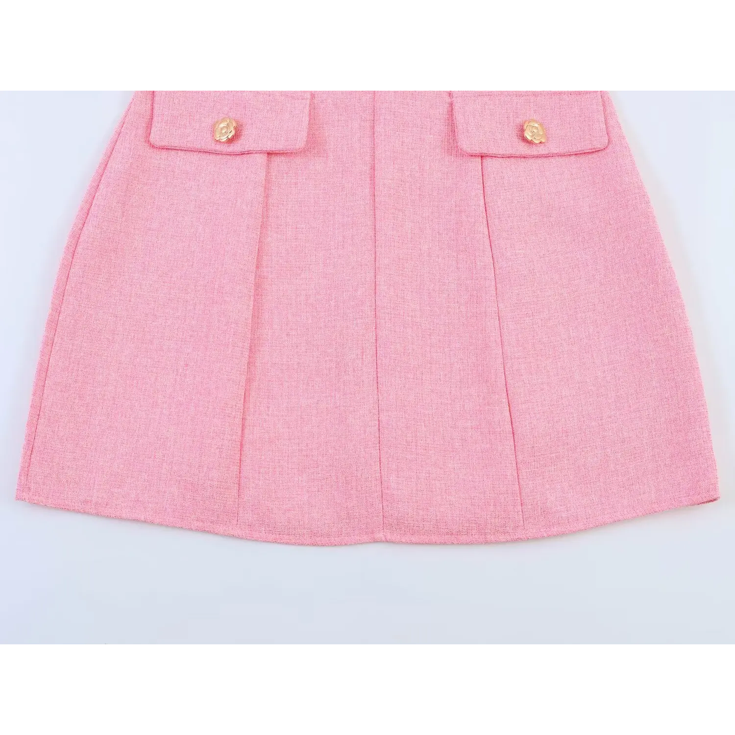 Flat shot of lower skirt section, two symmetric patch pockets each with gold camellia button, straight tailored mini hem