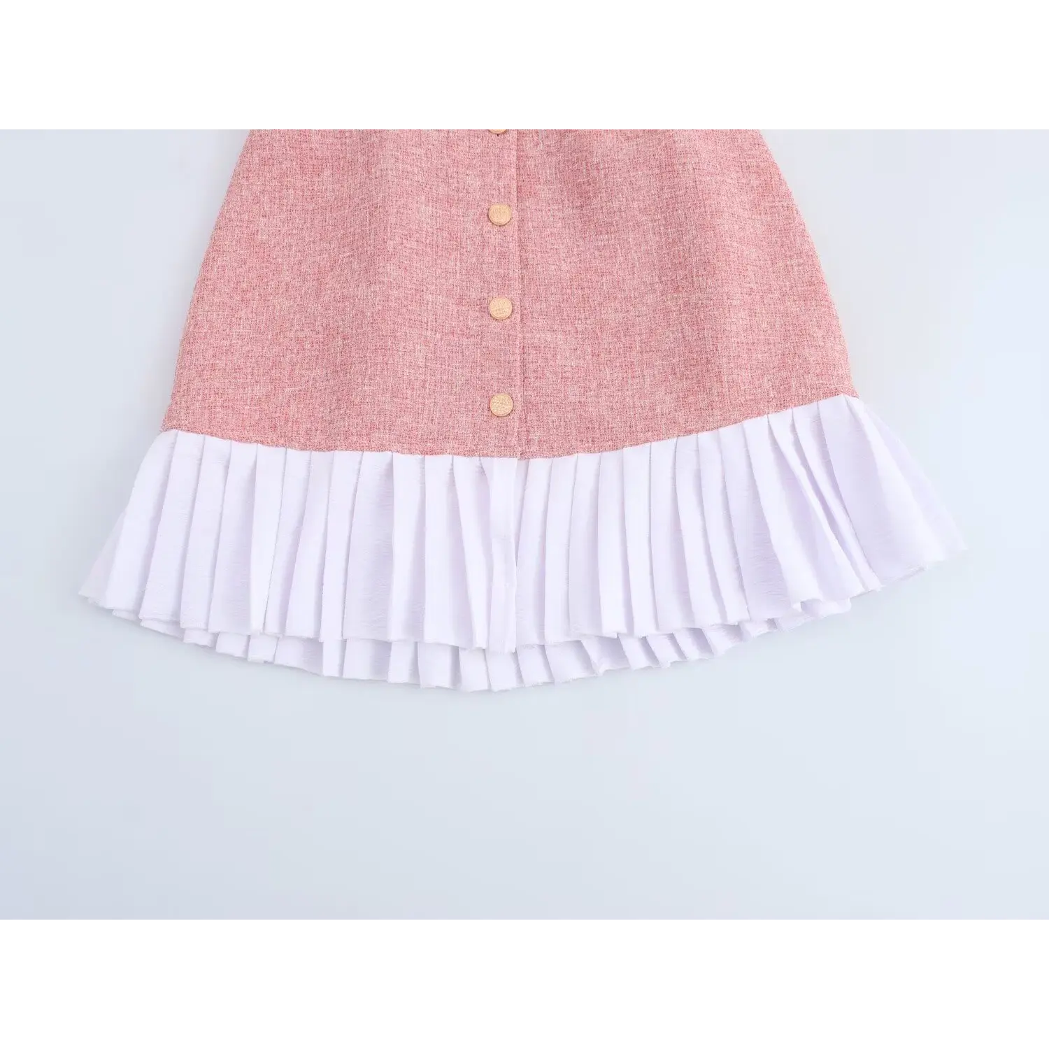 Close-up skirt hem, thick pink tweed upper panel spliced with uniform white crinkle fabric box pleats, neat horizontal seam