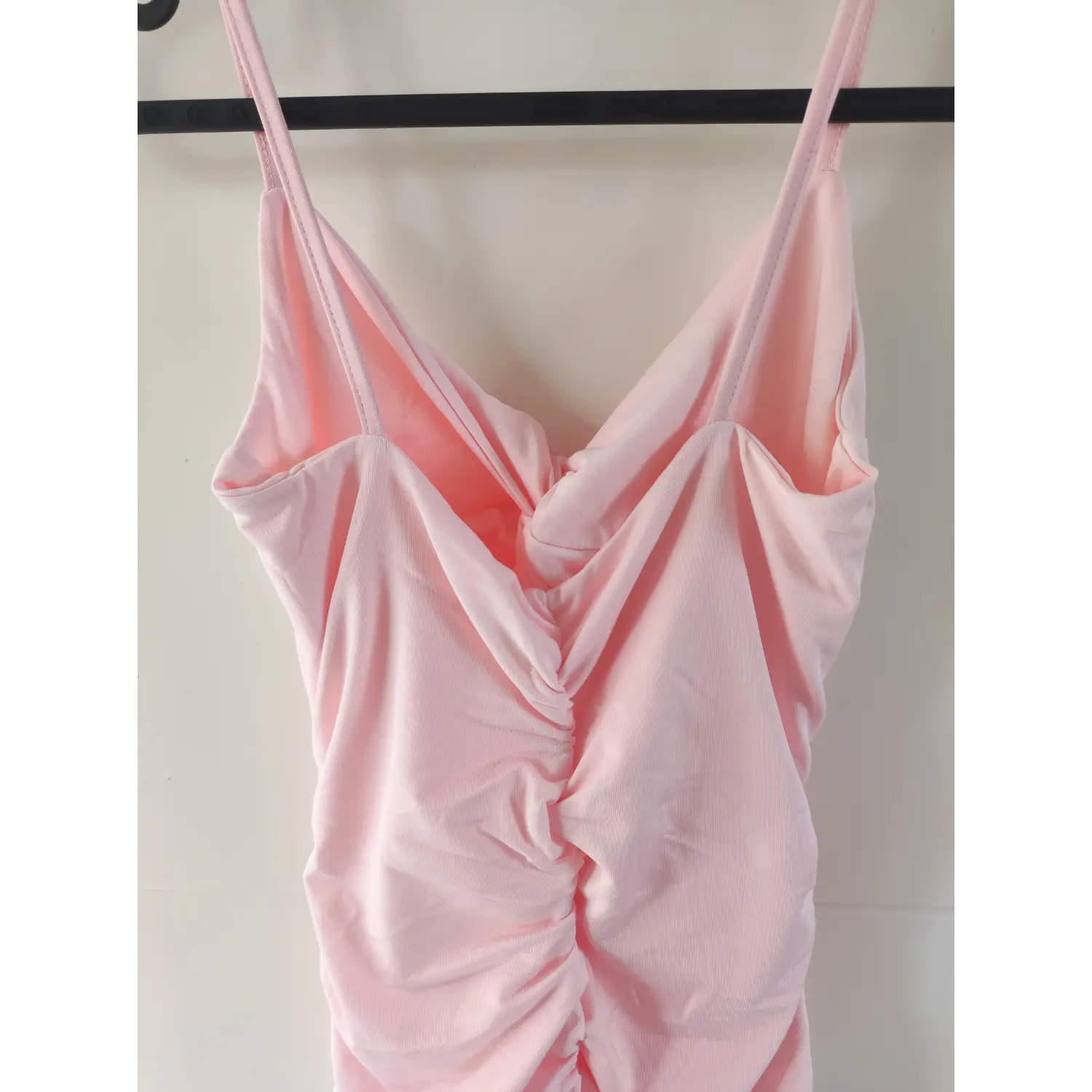 Close‑up view bust twist knot and front ruched detail of pink spaghetti strap mini dress