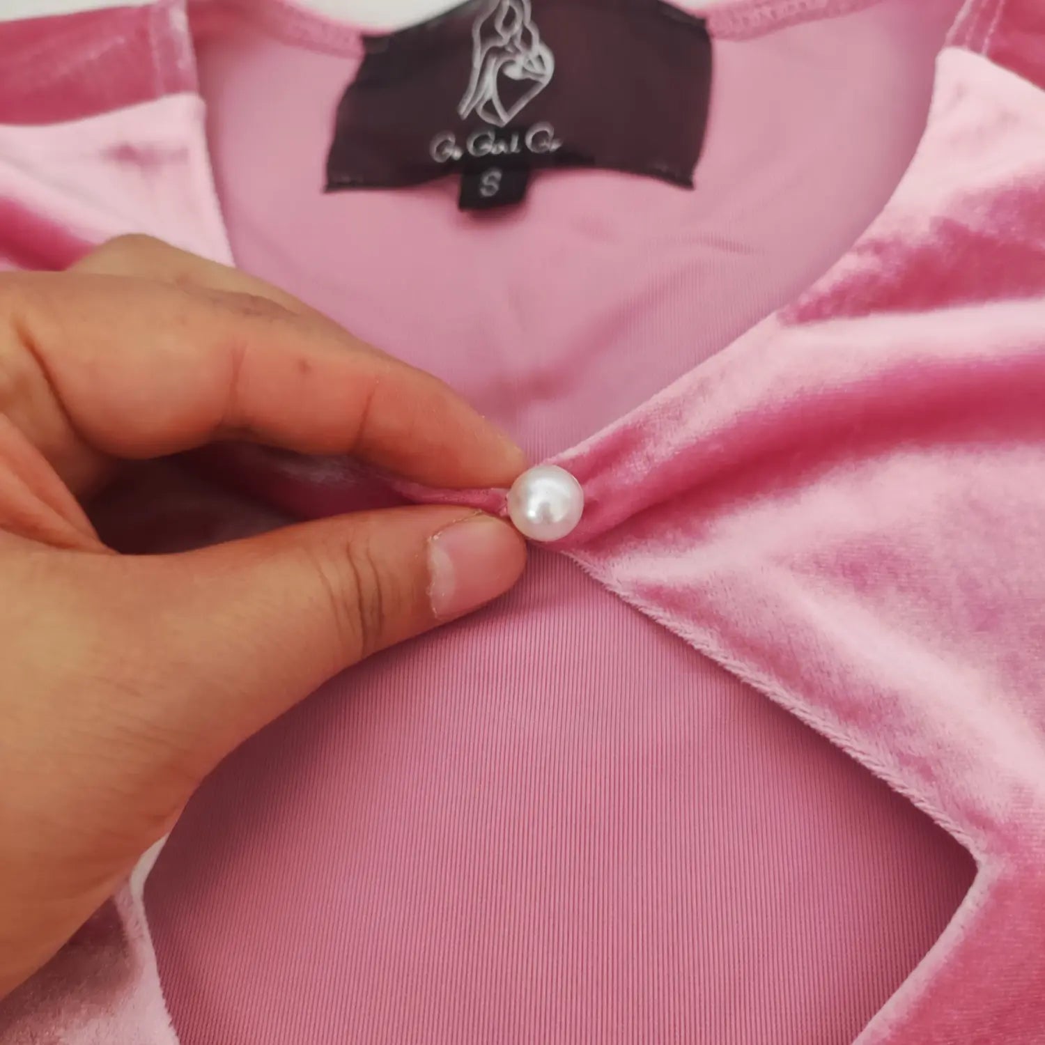 neckline-detail-view | Pink velvet midi dress close-up, front diamond cutout, pearl bead button, inner clothing label, three quarter sleeve swing dress