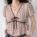 Front lifestyle shot on model of pink floral stripe blouse, V neck lace & ribbon detail, puff sleeves, fitted peplum waist, sweet vintage casual top