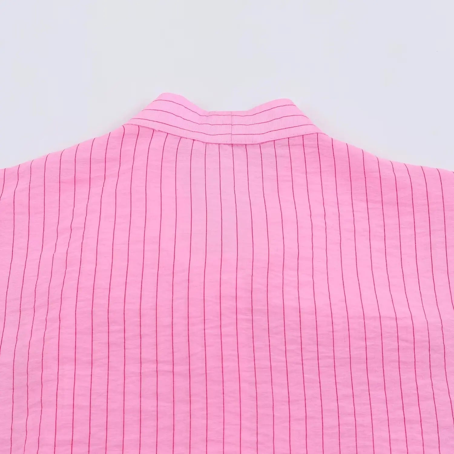 Flat closeup rear stand collar seam on pink thin vertical stripe tie neck blouse