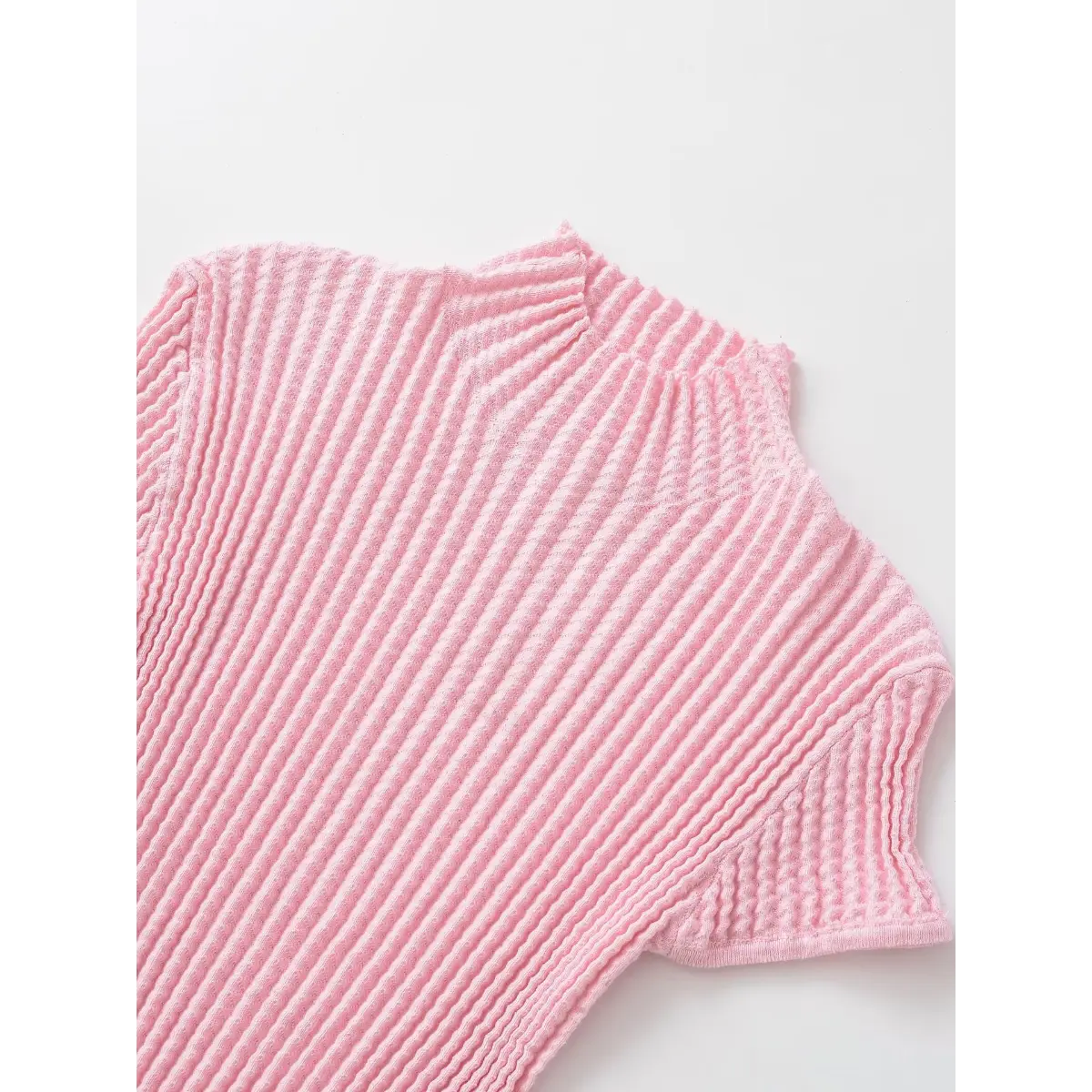 Front view of the pink waffle-knit top, showing the mock neck, short sleeves, and all-over textured pattern