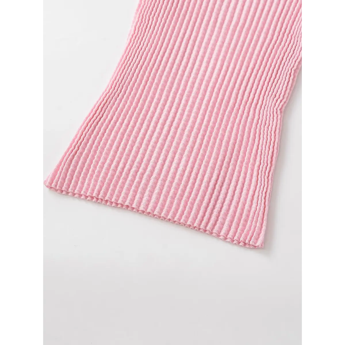 Hem view of the pink waffle-knit top, showing the ribbed texture and scalloped edge