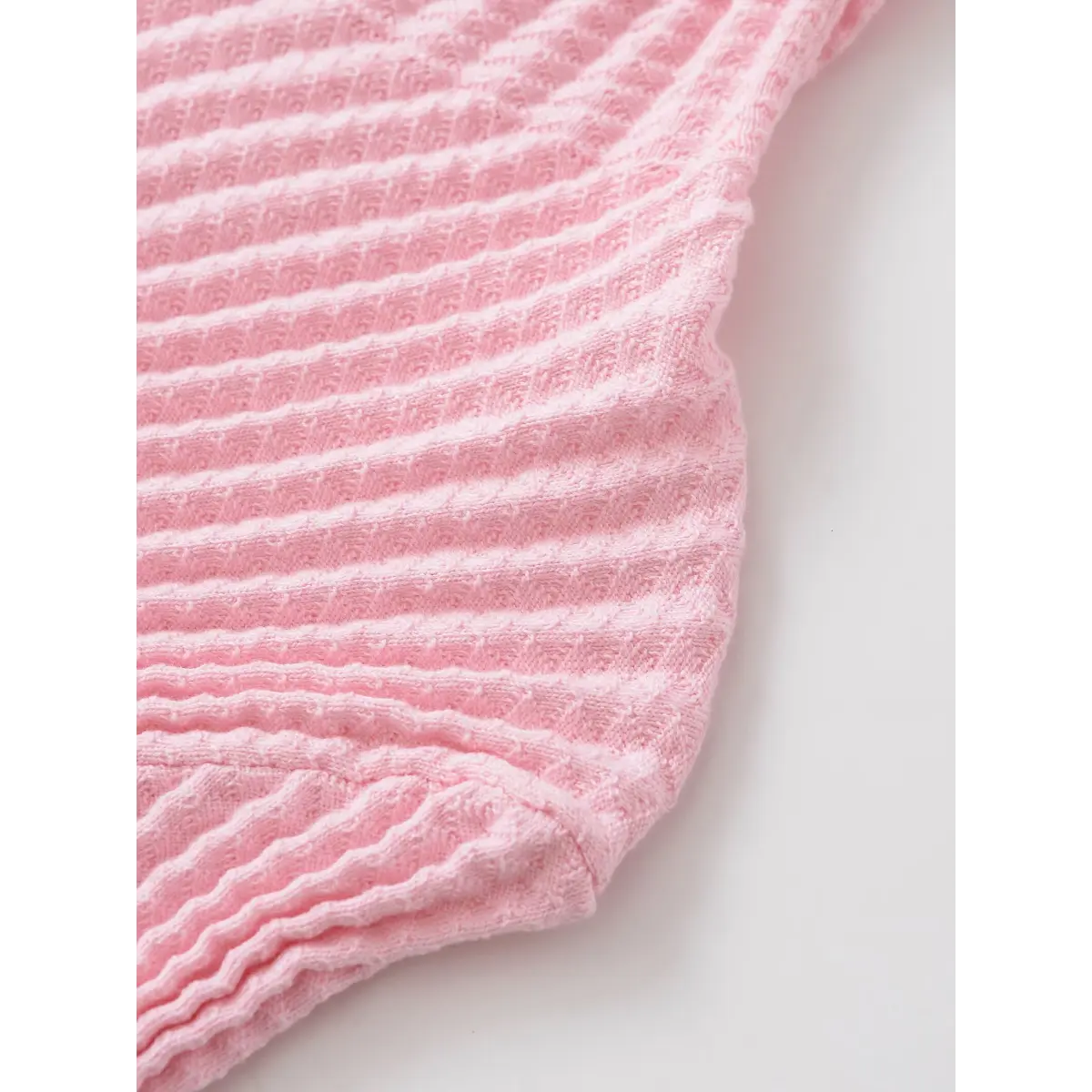 Side view of the pink waffle-knit top, highlighting the textured pattern and curved seam