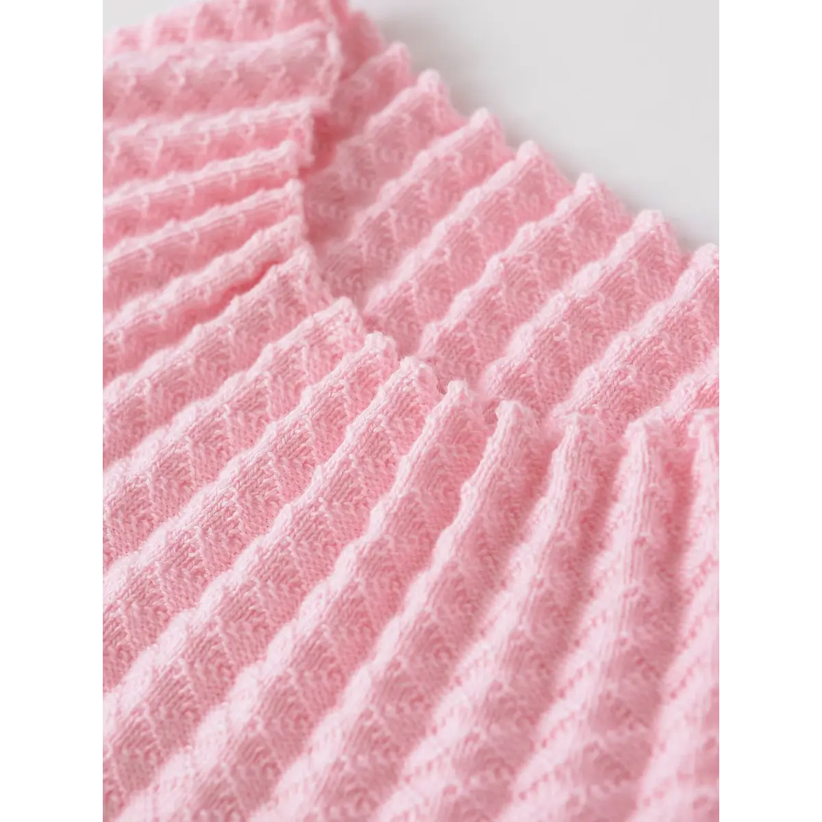Close-up of the pink waffle-knit fabric, showing the intricate ribbed pattern