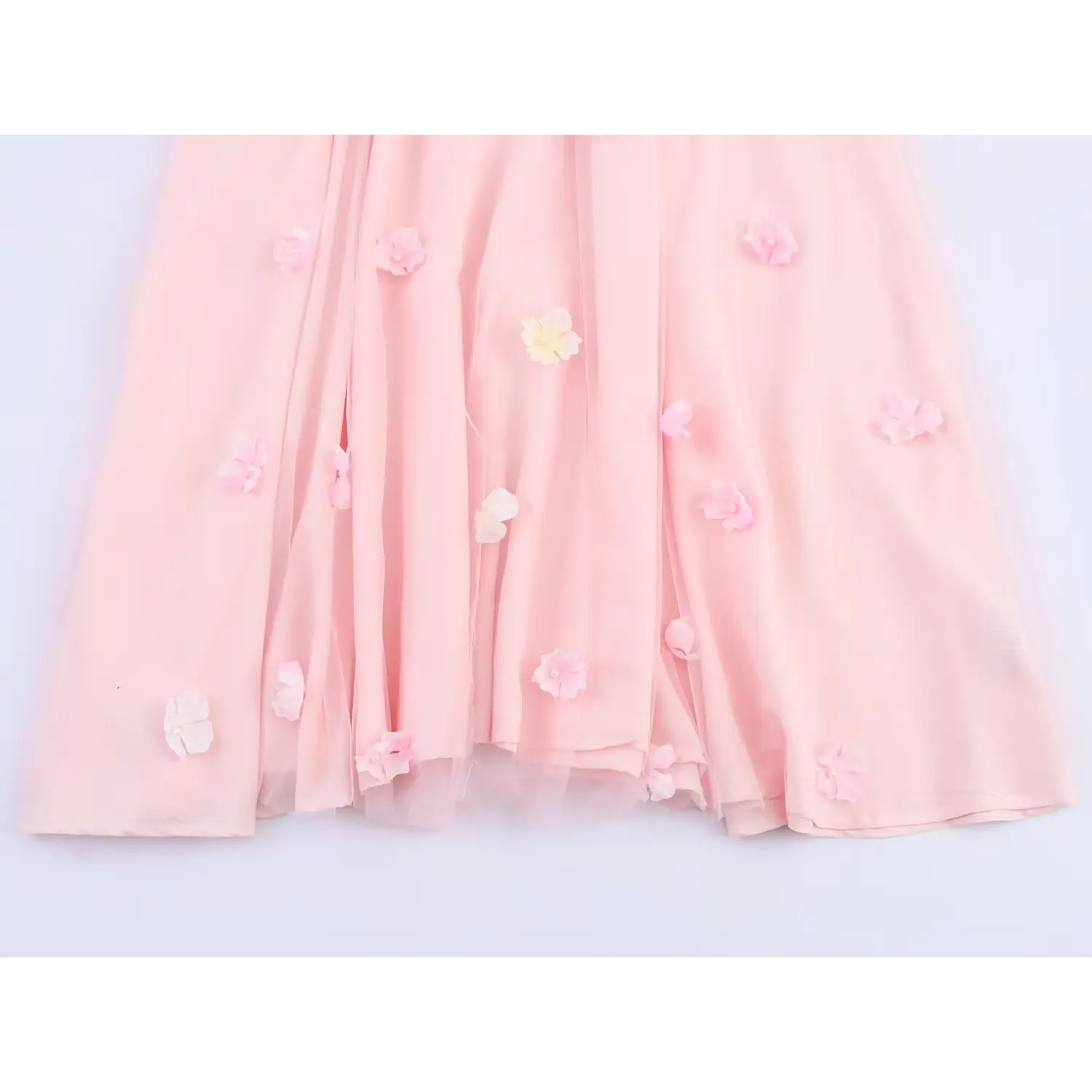 Close‑up of pleated skirt with scattered 3d flower appliques