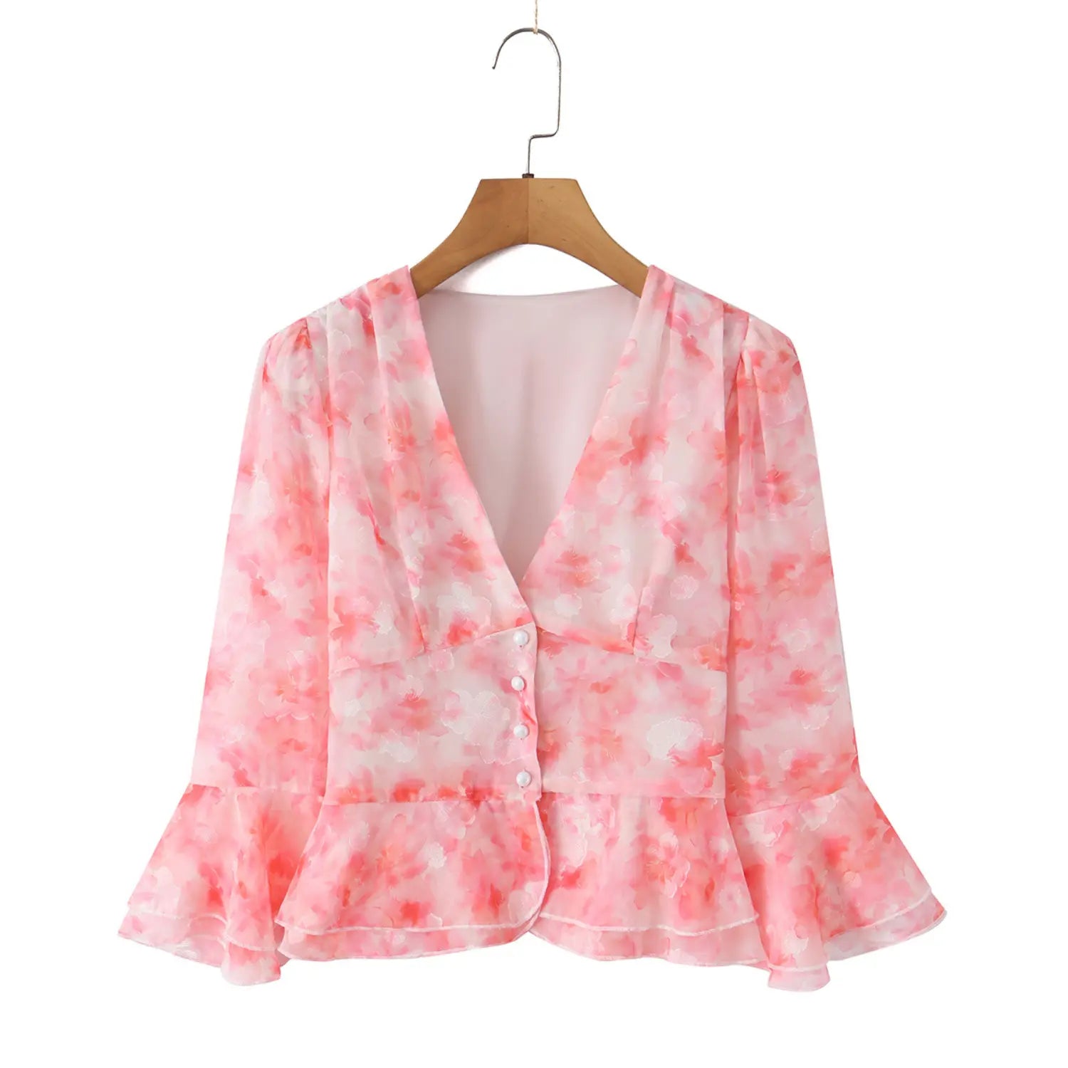 Front view of pink floral chiffon peplum blouse on wooden hanger, v‑neck, bell flare sleeve, front pearl buttons, cropped peplum hem