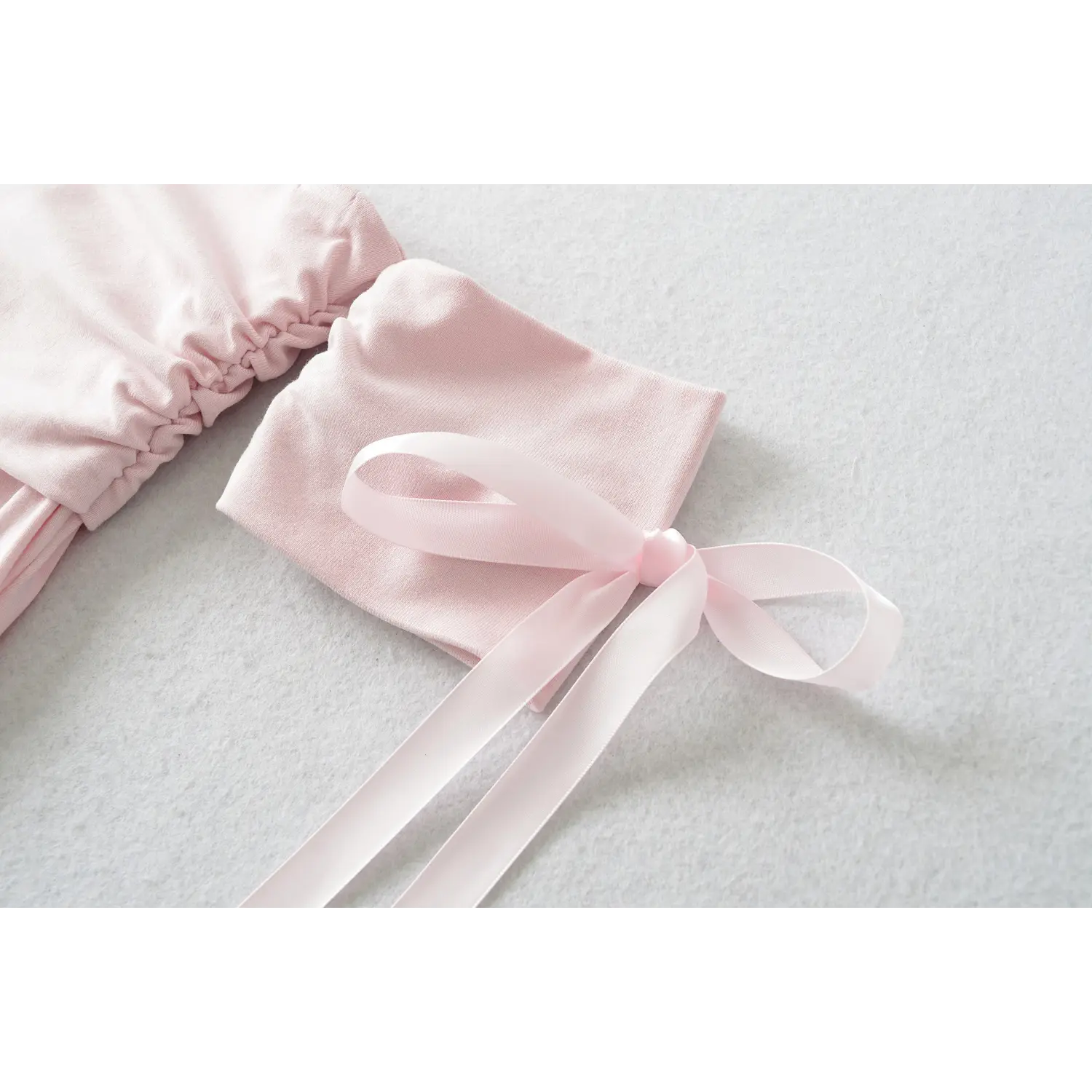 Close-up of detachable light pink short sleeve with long satin ribbon bow for off shoulder fitted top