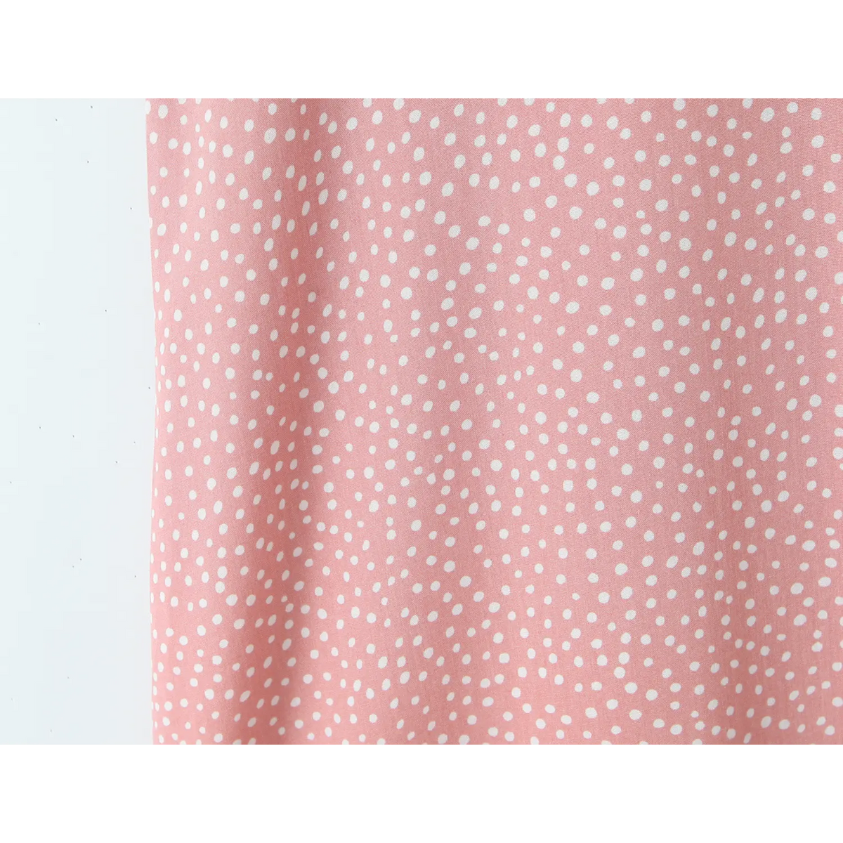 Macro close‑up of pink fabric with small white polka dot print
