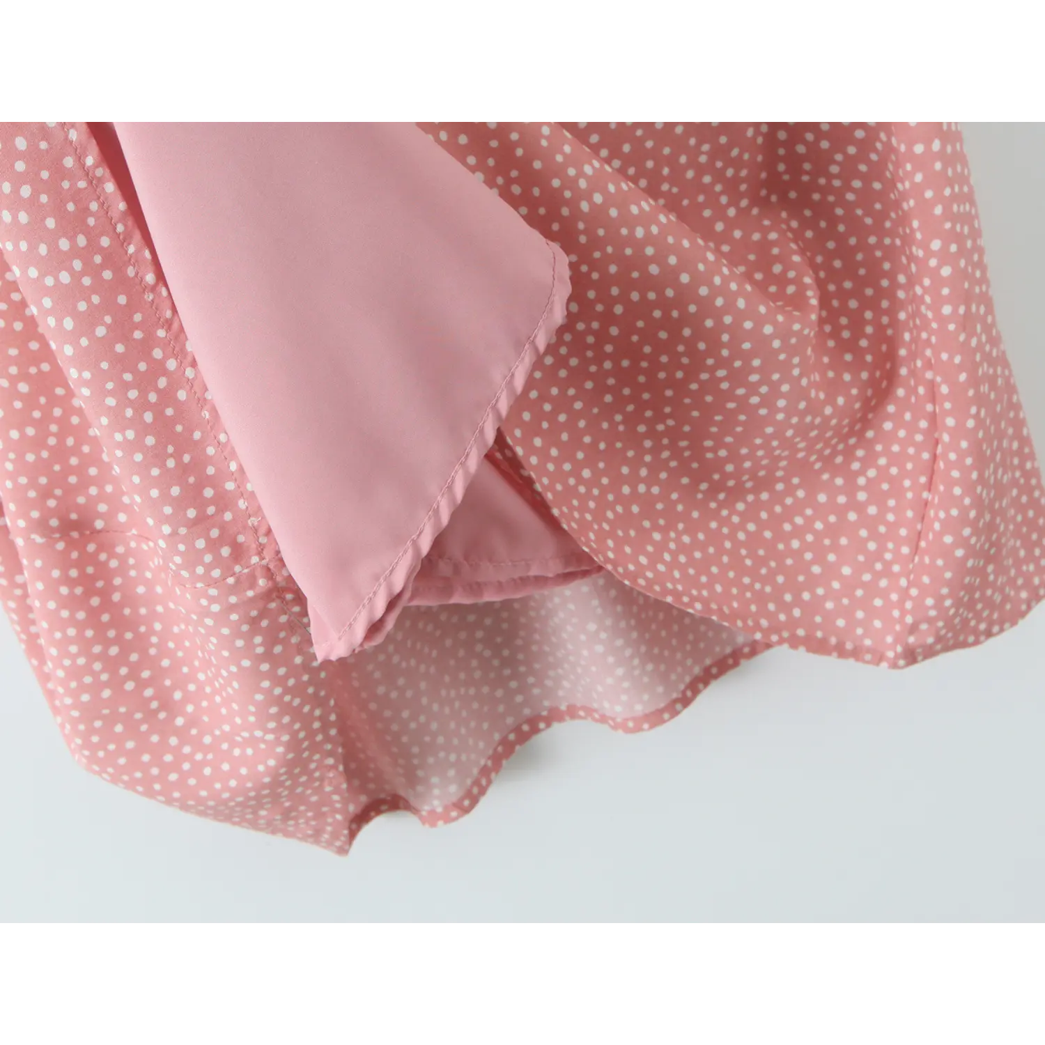 Close‑up of solid pink inner lining under polka dot outer fabric