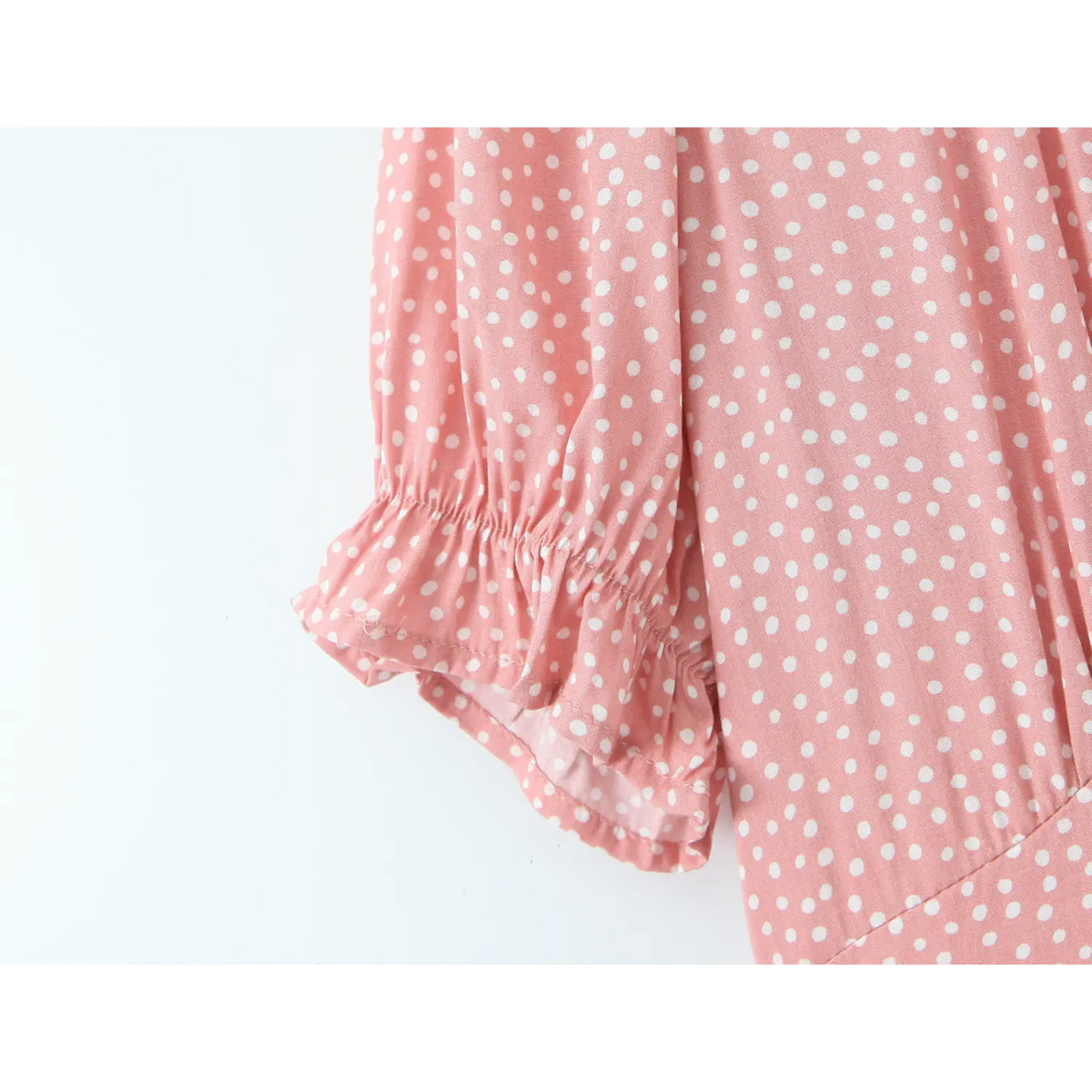 Close‑up of short ruffled puff sleeve cuff, pink white polka dot fabric